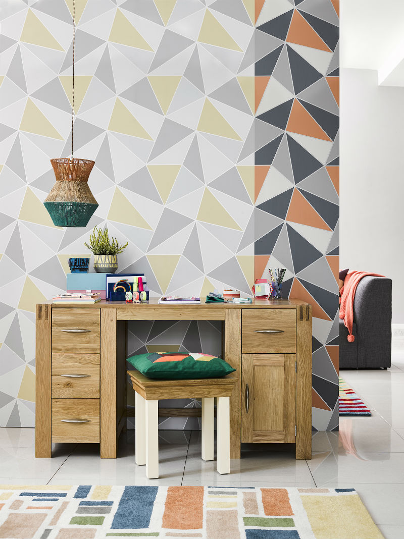 Natural wood office desk with geometric wallpaper feature