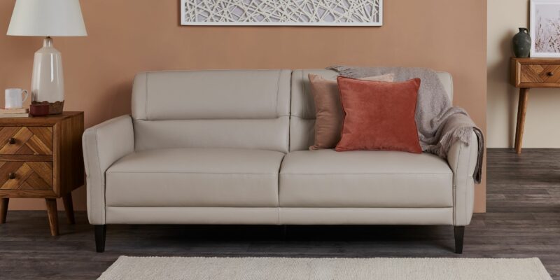 Beige leather sofa styled with rust coloured accessories and pair with Parquet furniture.