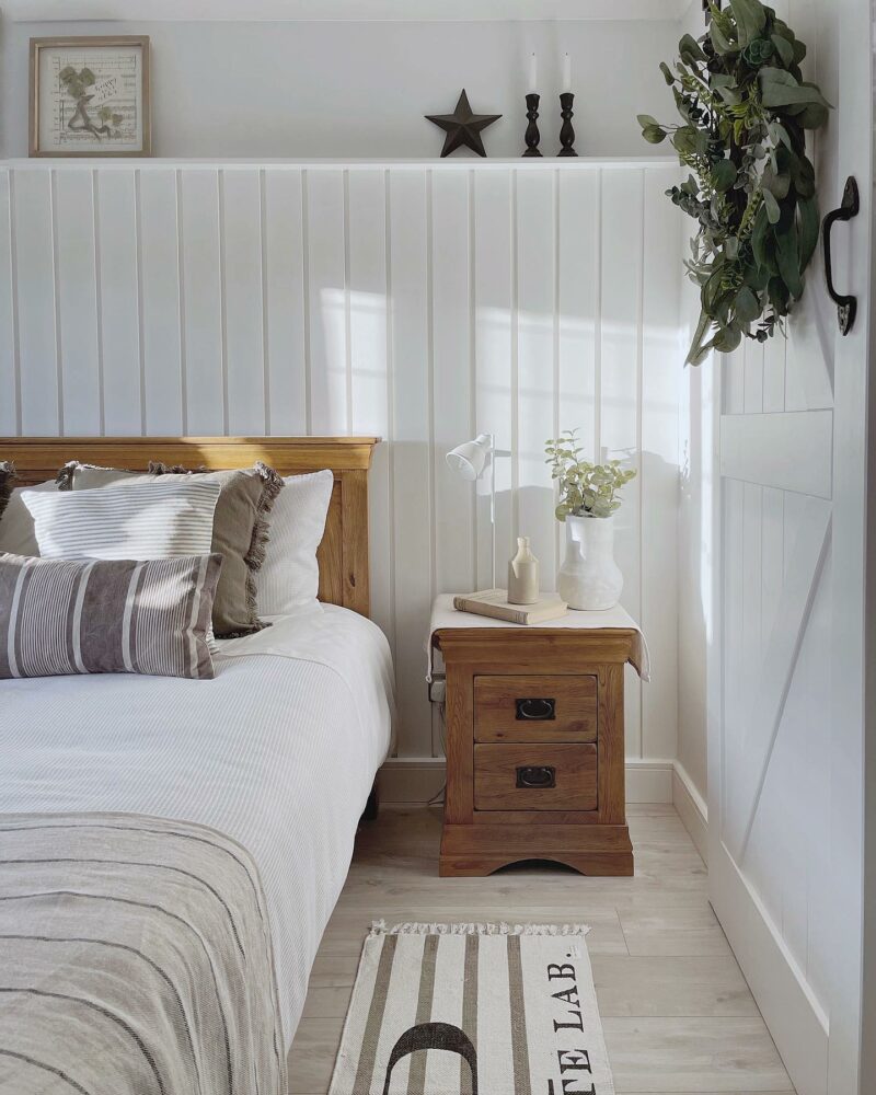 White country cottage-style bedroom with rustic oak bedside table and matching bed.