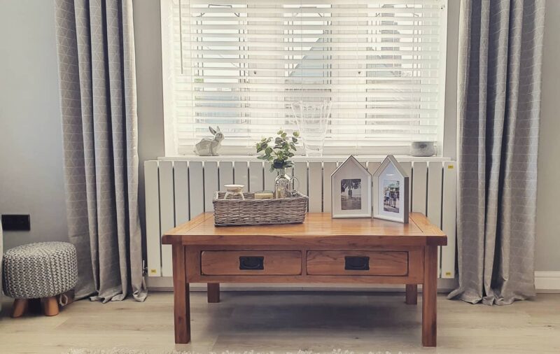 Original Rustic coffee table next to a radiator in a contemporary home with grey curtains and accessories.