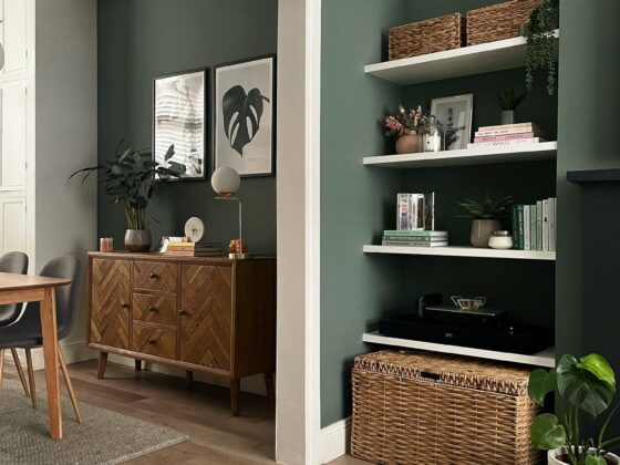 Living room-diner with walls painted in sage green and natural oak furniture.
