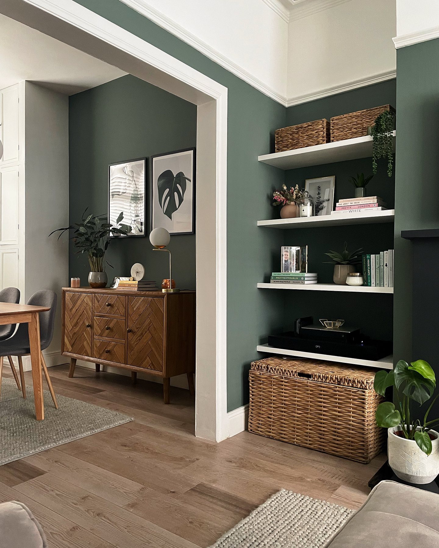 Living room-diner with walls painted in sage green and natural oak furniture.