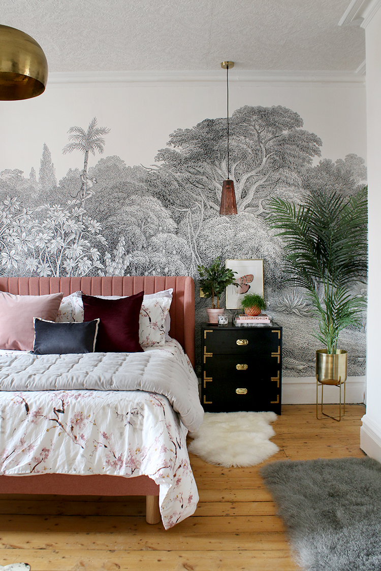 Pink bed in bedroom with ornate wallpaper