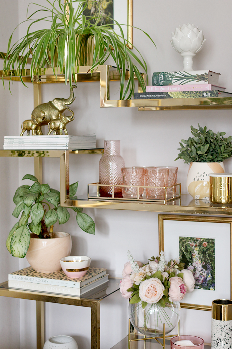 Gold ornate shelving with plants and pink ornaments