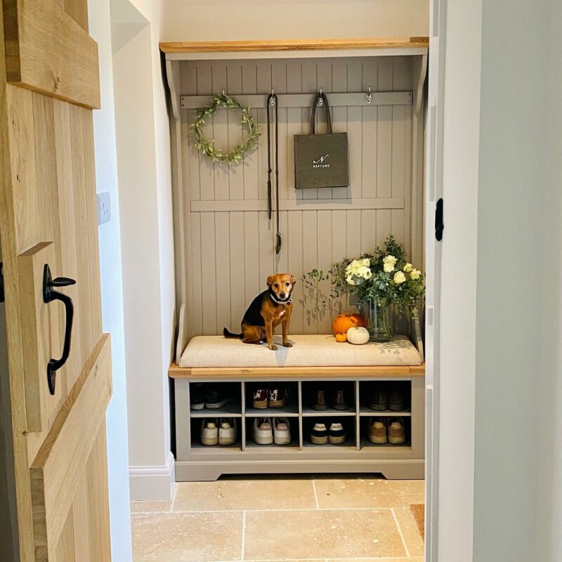 Oak Furnitureland St. Ives grey painted hallway shoe and coat unit with a dog sitting on the cushion.