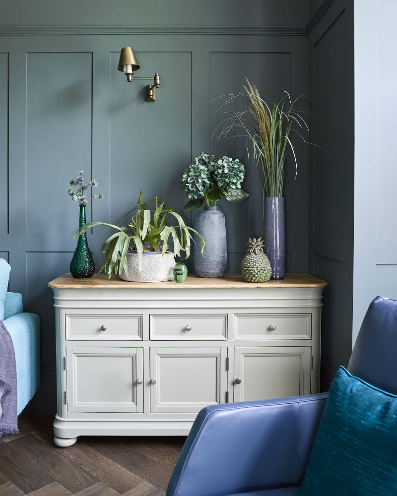 Sage green painted sideboard topped with a variety with house plants