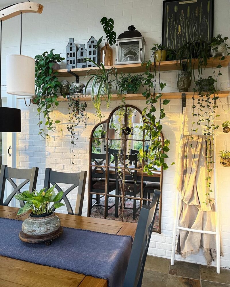 Highgate dark blue and rustic oak dining table in a room with painted brick wall and lots of plants.