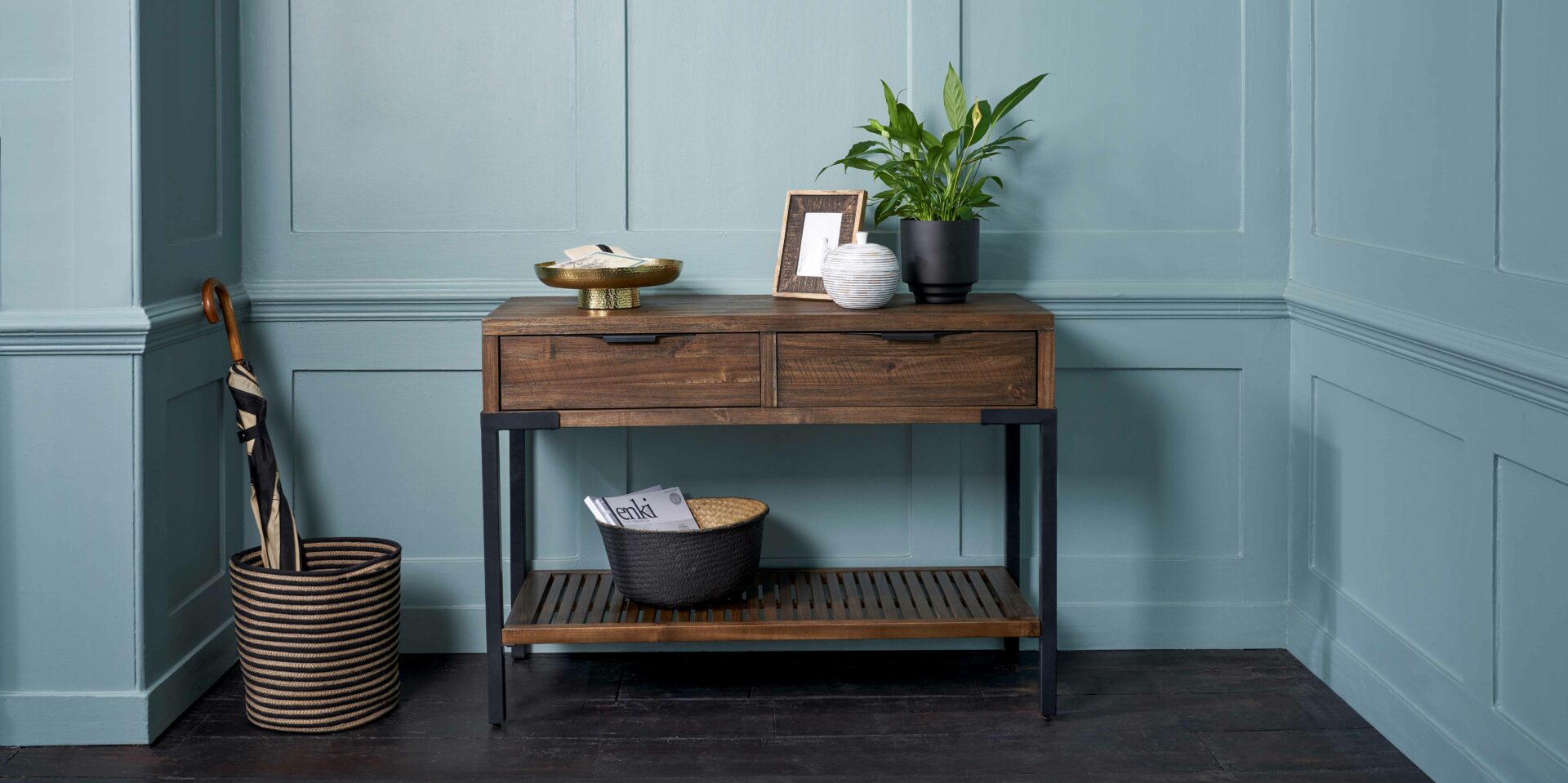Oak Furnitureland Detroit dark glazed console table against a blue backdrop.
