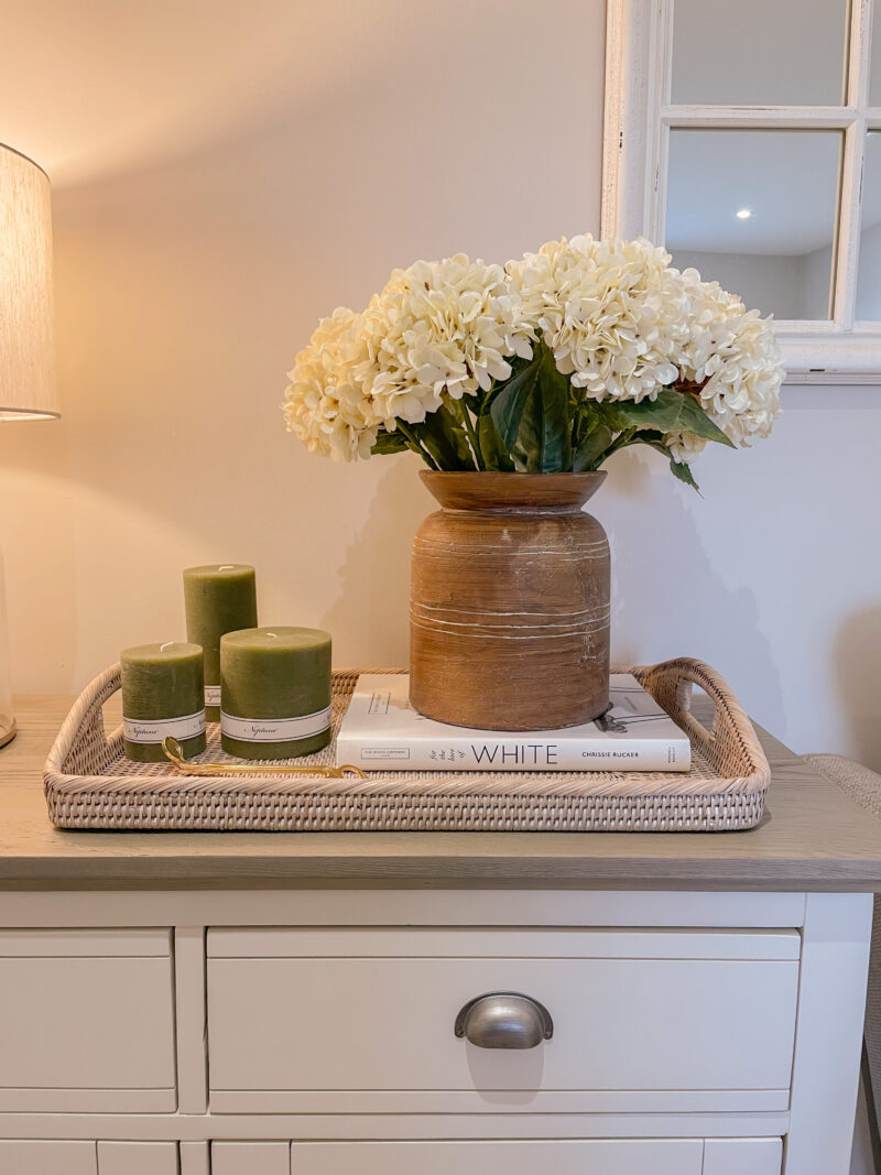 Oak Furnitureland Brompton small sideboard styled with white flowers and olive green candles.