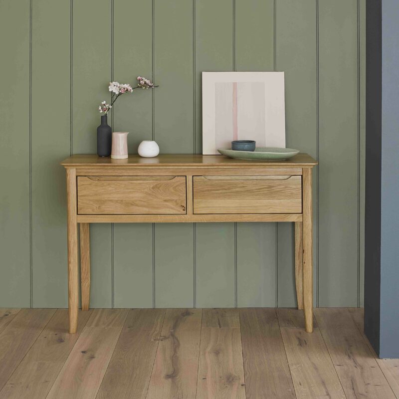 Copenhagen console table styled wtih decorative accessories in a green panelled room.
