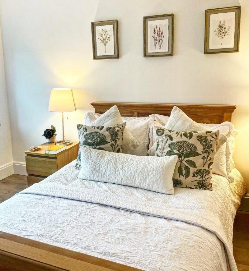 Neutral farmhouse-style bedroom with a rustic oak bed and industrial-style oak bedside table.