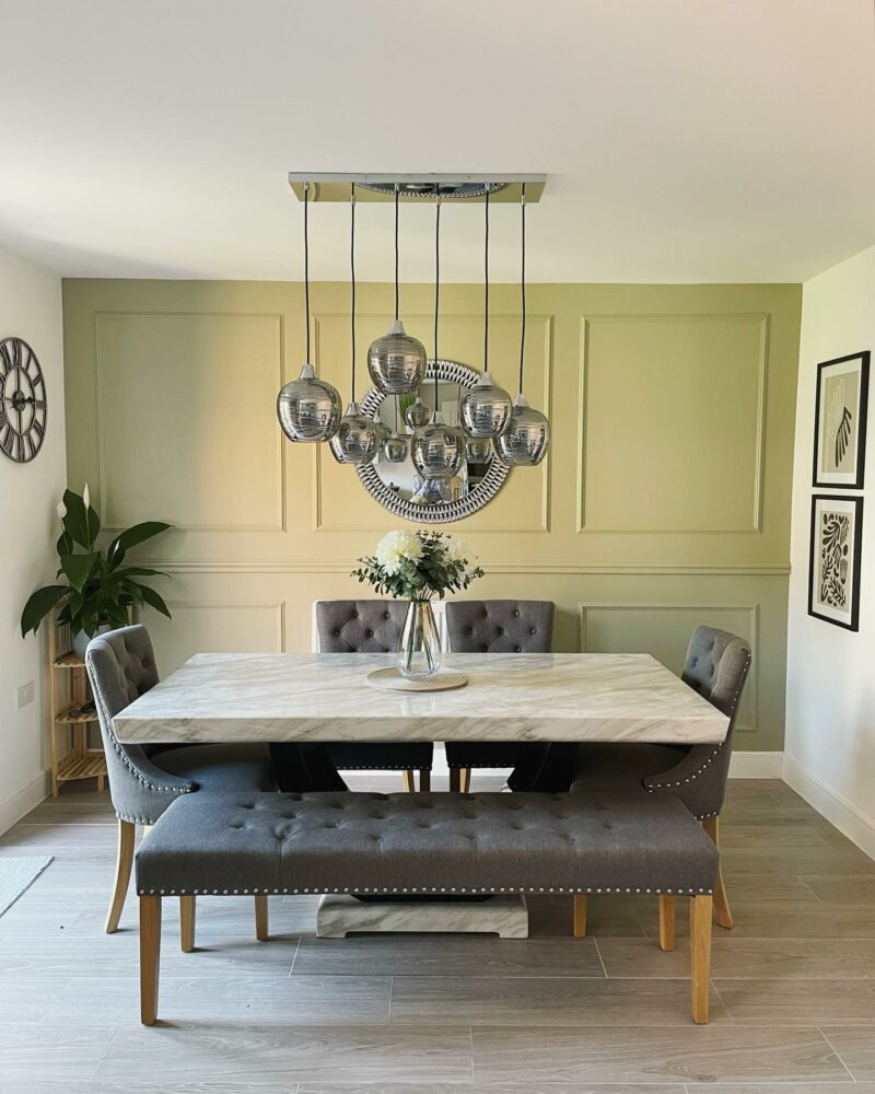 Oak Furnitureland Vivien upholstered grey bench and chairs in a living room with green panelled walls.