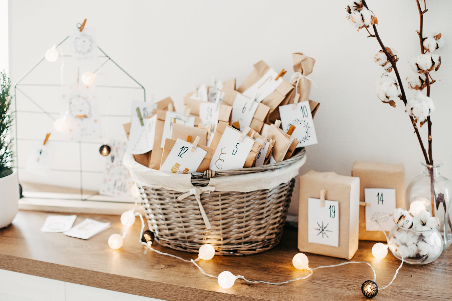 DIY advent calendar in a wicker basket on a table with fairy lights.