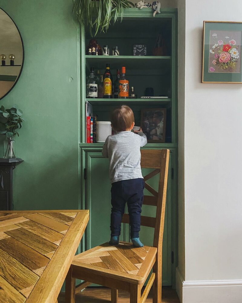 Parquet dining set in green kitchen with open shelving