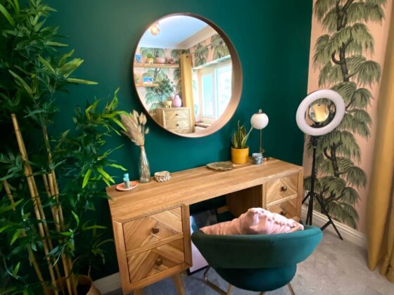 Parquet dressing table in a room with a bright green wall and botanical wallpaper.