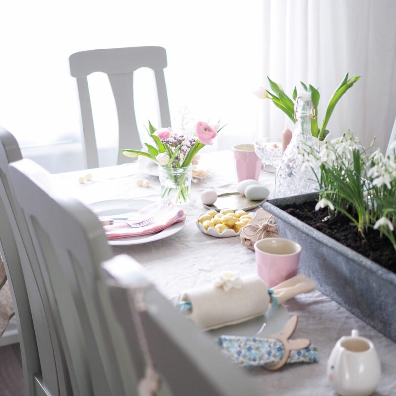 Oak Furnitureland grey painted table set up for Easter meal, with spring flowers and Easter decor.
