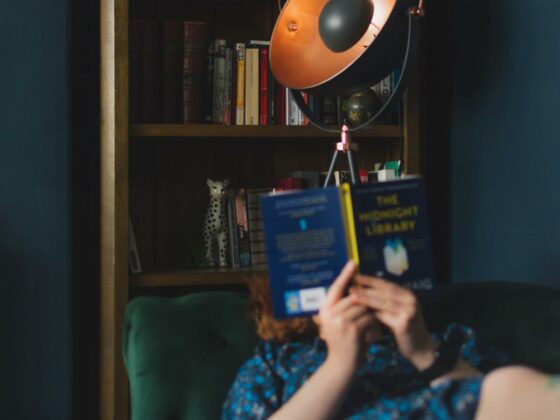 Oak Furnitureland oak bookcase featured in the background behind a woman lying on a green sofa reading a book.