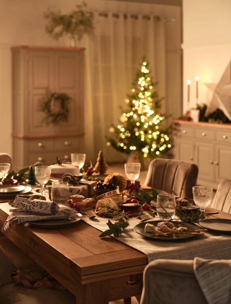 Dorset natural oak dining table set for Christmas with a twinkling tree in the background.