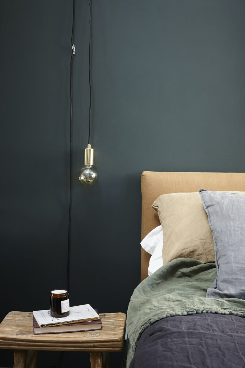 Simple bedroom with dark blue walls and relaxed bedding.