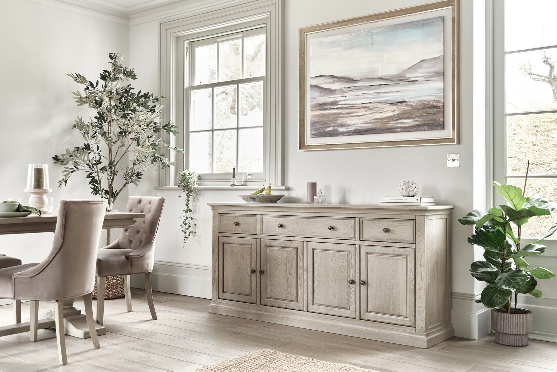 Oak Furnitureland weathered oak Burleigh furniture, including large sideboard and dining table, with art and houseplants.