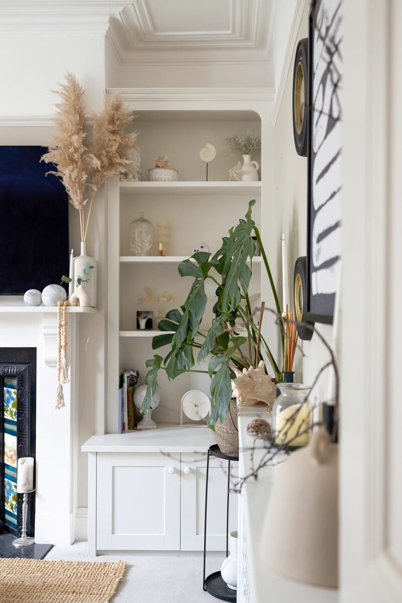 An alcove-living room-tiled fireplace-wall shelving-house plant-pampas grass-neutral decor