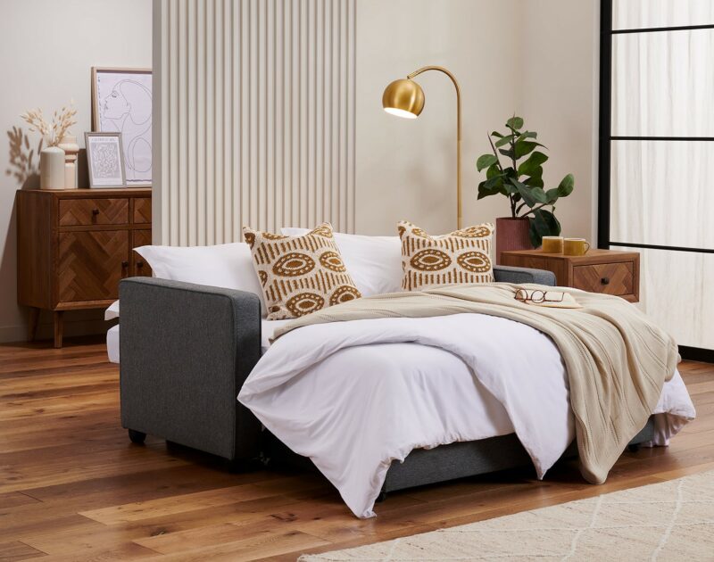 A sofa bed, side table and sideboard-living room furniture-dark grey sofa bed-wooden side table-brass floor lamp-wooden panelled sideboard
