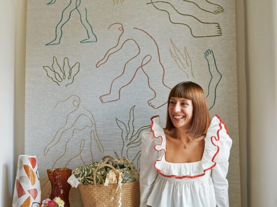 A person, basket, wall hanging, and vases-living room furniture-Katherine Ormerod-stretched textile panel-abstract artwork-frilly shirt-geometric patterned vase