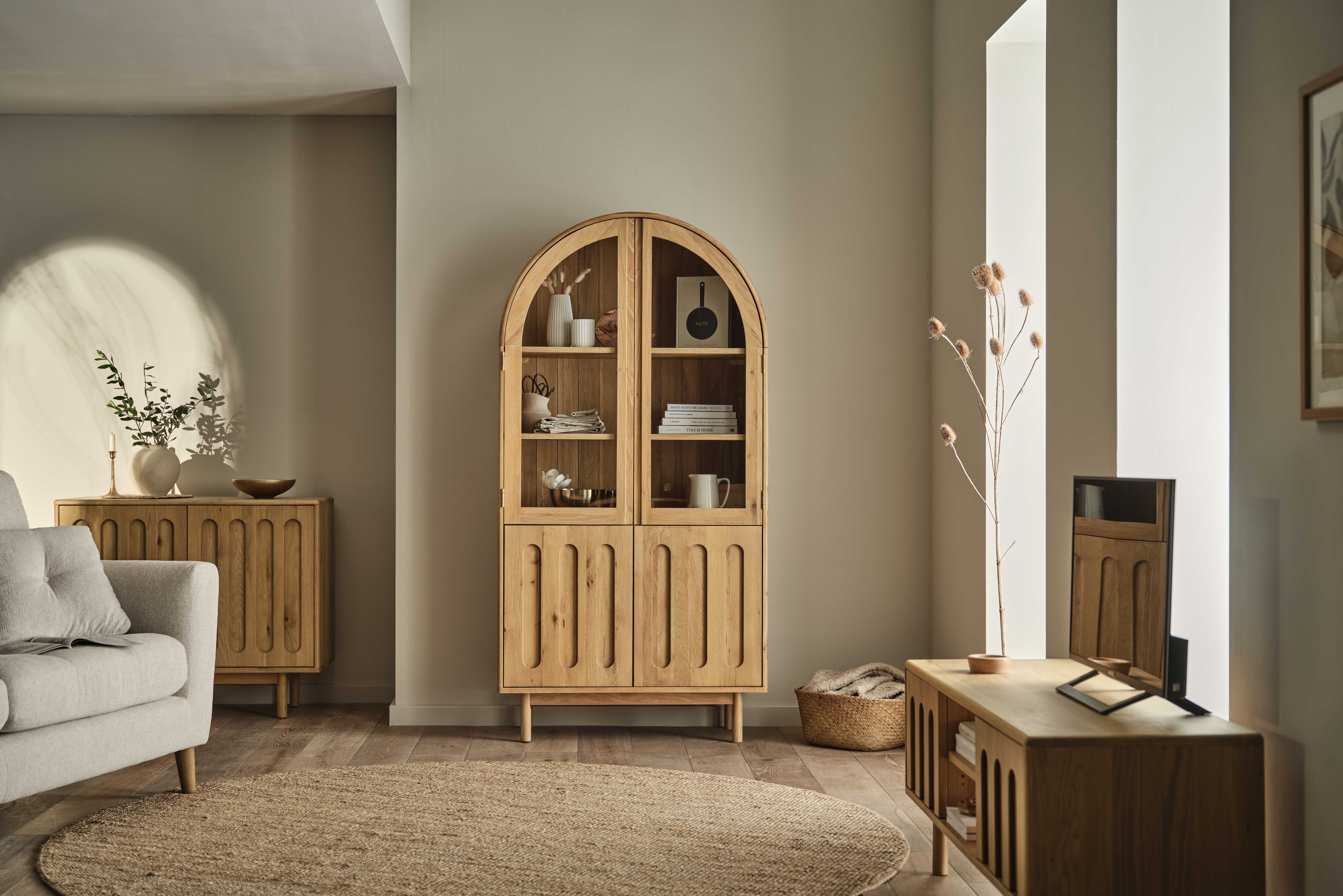 A sofa, TV unit, and cabinet-living room furniture-textured neutral rug-arched wooden display cabinet-pale wooden TV unit-cream sofa-neutral walls