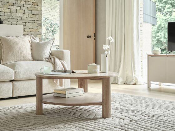 A sofa, coffee table, and TV unit-living room furniture-textured neutral rug-pale oak coffee table-cream sofa-neutral TV unit-clever storage-exposed brick walls-cream draped curtains