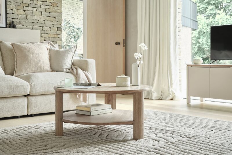 A sofa, coffee table, and TV unit-living room furniture-textured neutral rug-pale oak coffee table-cream sofa-neutral TV unit-clever storage-exposed brick walls-cream draped curtains