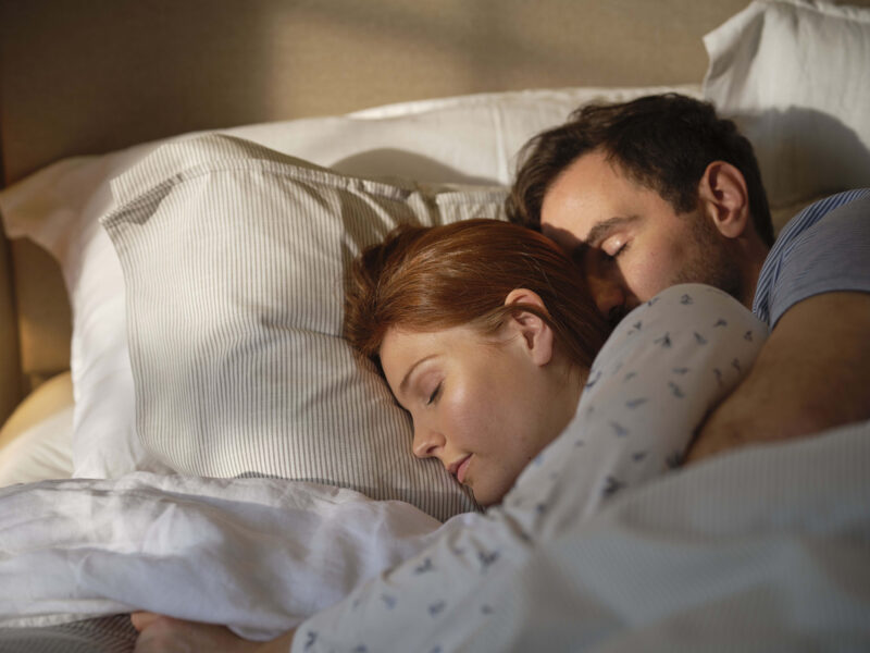 A couple in a bed-bedroom furniture-a man and woman sleeping in bed-morning light-neutral bedding-upholstered bed