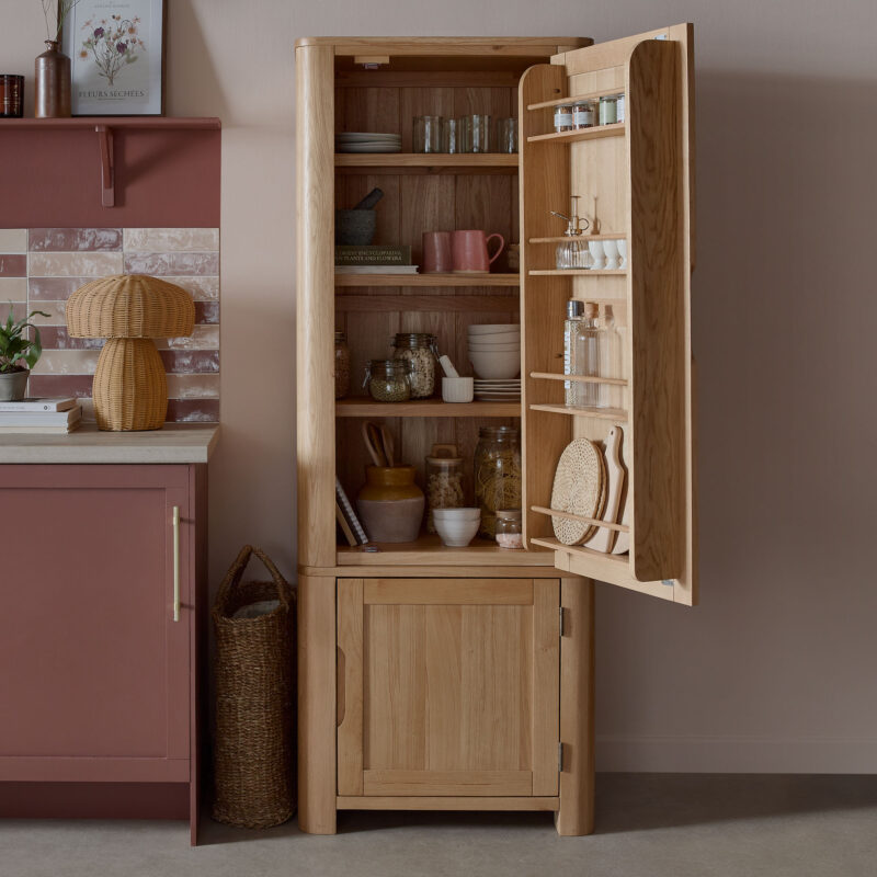 A kitchen larder-kitchen diner furniture-painted wooden larder-storage cupboards and drawers-crockery-storage jars-woven baskets-chopping boards-blush walls-burgundy kitchen-mushroom woven lamp