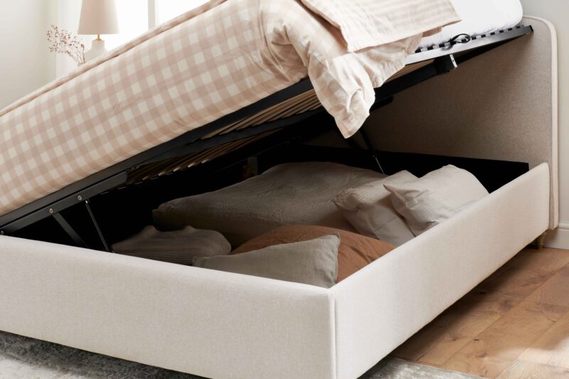 A bed-bedroom furniture-beige ottoman storage bed-earthy coloured cushions-neutral ginham bed linen-wooden floor